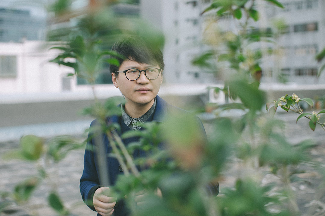 Trevor Yeung 在刺點畫廊的天台。他面前的桂花樹,是他去年在香港巴塞爾藝術展上個人展《遊園:不太容易做綠色》中使用的創作材料。攝:王嘉豪/端傳媒