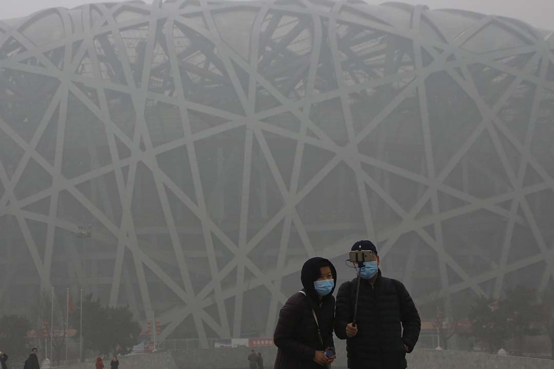 旅客在雾霾笼罩下在鸟巢体育馆前合照。摄:Kim Kyung-Hoon/REUTERS
