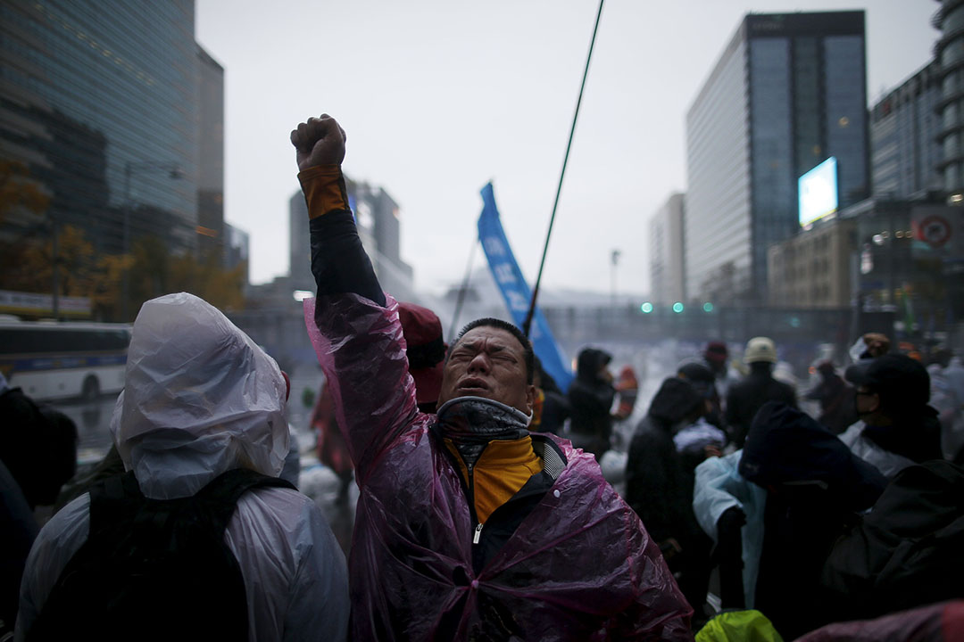 反政府示威者被警方的催泪水剂射中后高举右手。摄:Kim Hong-Ji/REUTERS