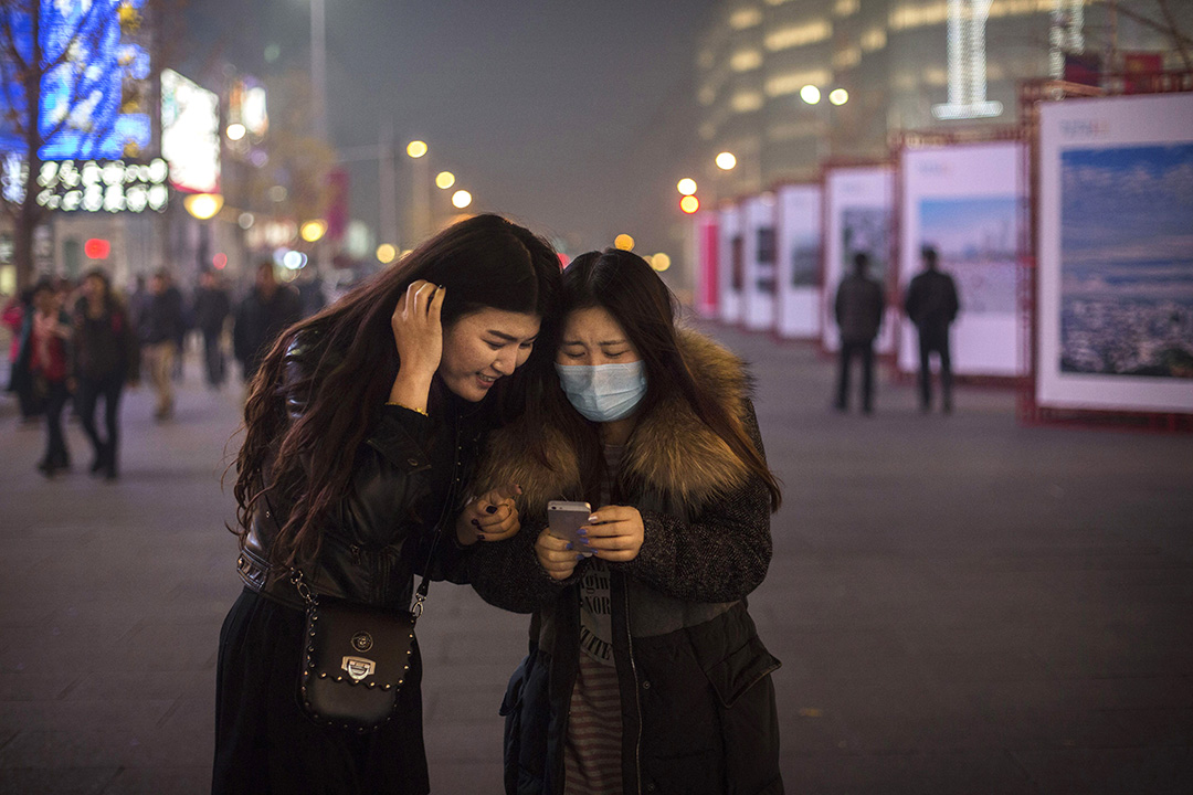 兩位女士在北京街頭低頭看手機上的信息。攝：Kevin Frayer/GETTY