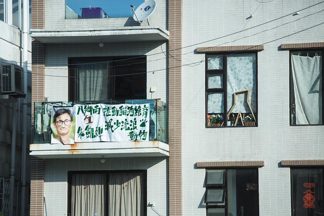 朱凱迪向八鄉居民徵求借出家中陽台,掛起他以循環再用的廢棄橫額加工而成的橫額。摄 : 王嘉豪/端传媒